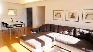 A modern living room with a sectional sofa, a dining table with chairs, and framed artwork on the wall. - Refuge with a wonderful view (MERAN)