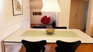 A dining area with a white table, black chairs, a red chair, a white lamp, and a framed picture on the wall. - Refuge with a wonderful view (MERAN)