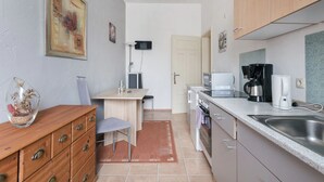A compact kitchen with a dining area, wooden cabinets, a microwave, a coffee maker, and a small refrigerator. - Apartment Elbflorenz (Dresden)