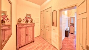 A hallway with a wooden cabinet, a mirror, and a door leading to a bathroom. - Apartment Elbflorenz (Dresden)