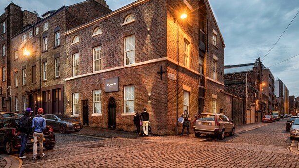 A historic brick building with a sign reading "town" on the facade, a cobblestone street, and parked cars. - York Street Studios (Liverpool)