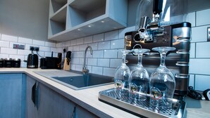 A modern kitchen with a stainless steel espresso machine, a sink, and a countertop with three clear glasses. - York Street Studios (Liverpool)
