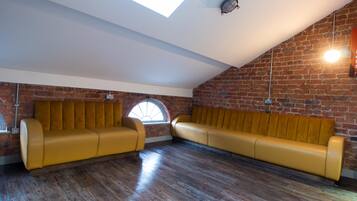 Ein Loft-Zimmer mit Ziegelwand, Holzboden und einem gelben Sofagarnitur.