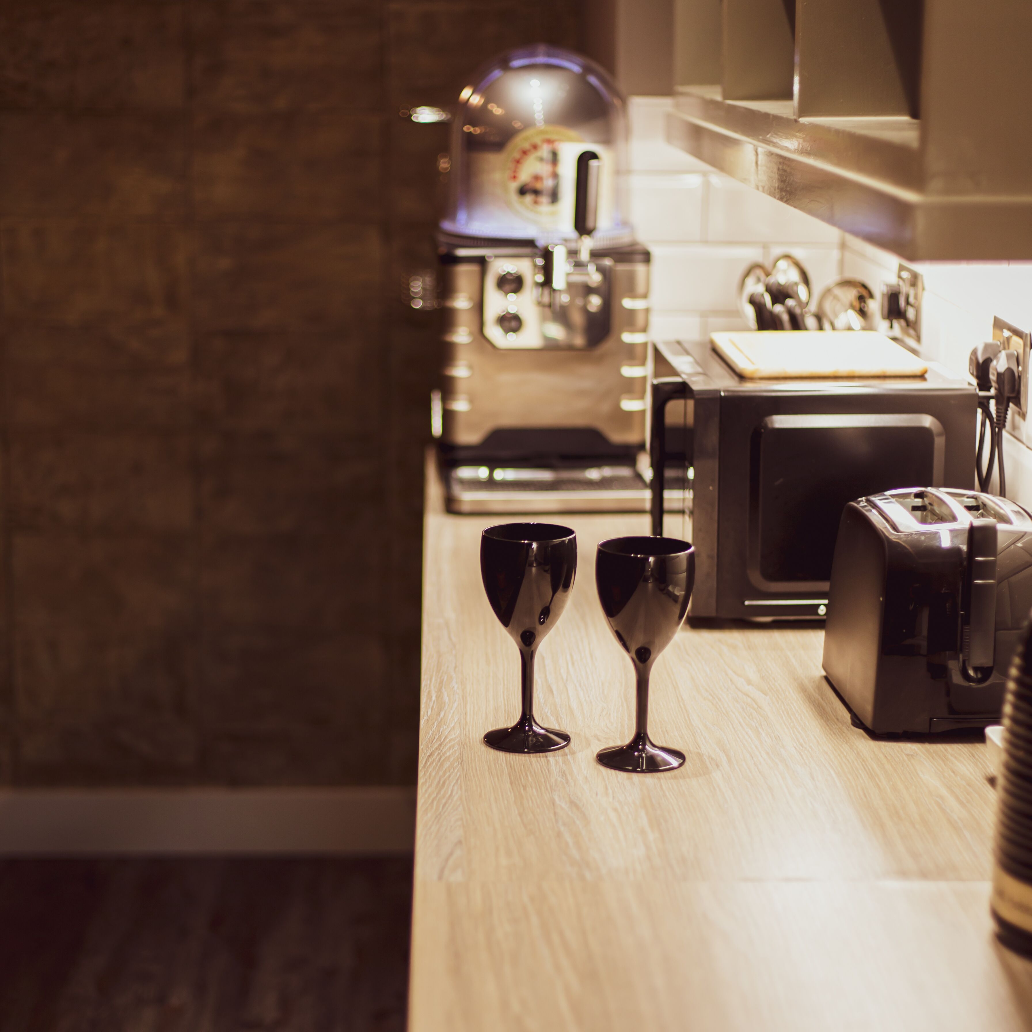 A kitchen with a coffee machine, a toaster, and two wine glasses on the counter.