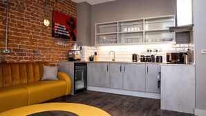 A modern kitchen with a brick wall, a yellow sofa, and a built-in dishwasher. - York Street Studios (Liverpool)