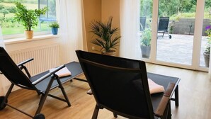 Une pièce équipée de deux appareils de musculation, d’une fenêtre avec des rideaux et donnant sur un jardin.