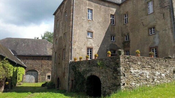 Un grand bâtiment en pierre, doté de nombreuses fenêtres et d’une arche centrale.