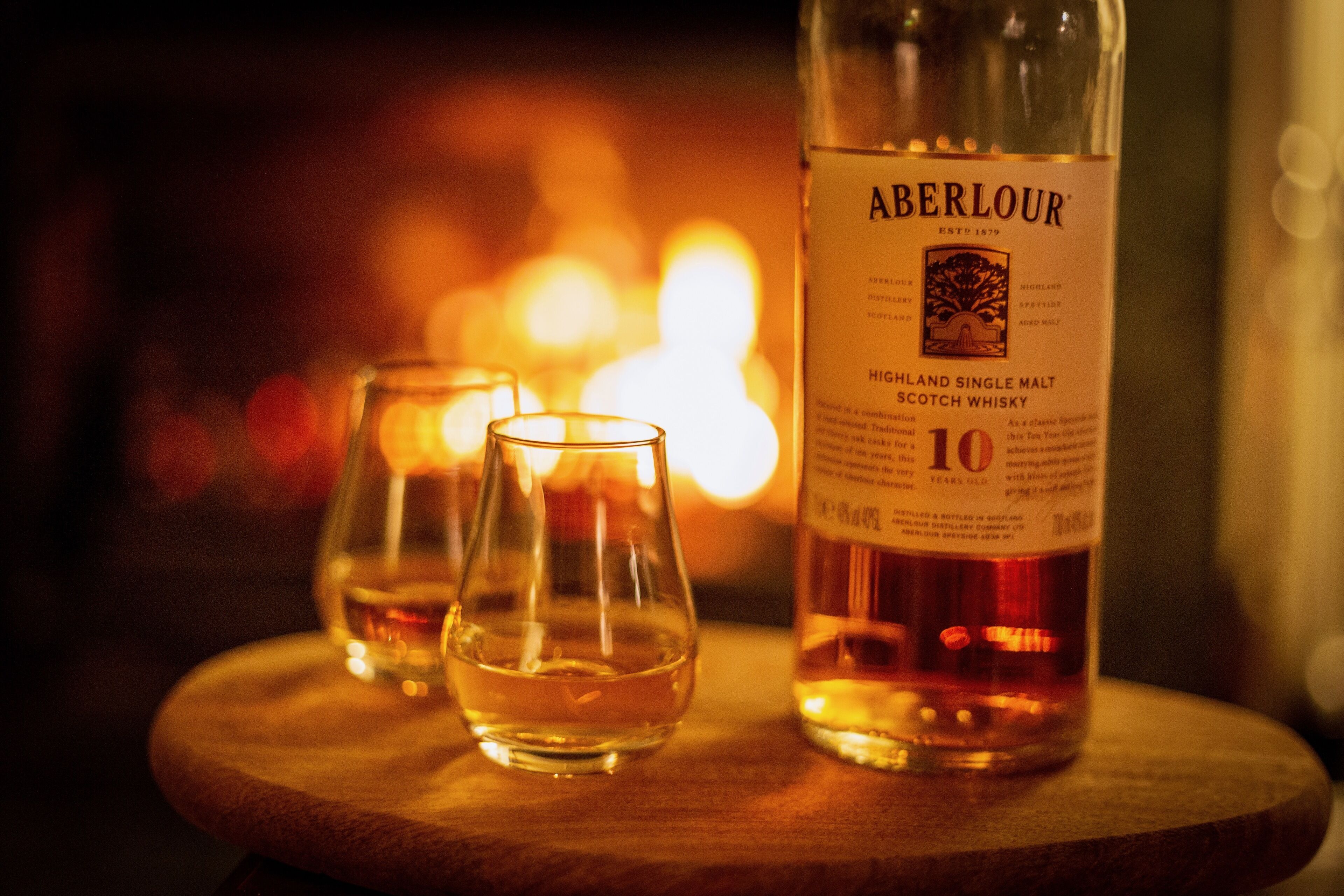 A bottle of Aberlour Highland Single Malt Scotch Whisky and two glasses on a wooden table.