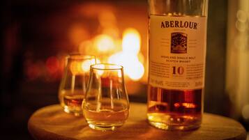 A bottle of Aberlour Highland Single Malt Scotch Whisky and two glasses on a wooden table.