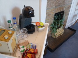 Una kitchenette con cafetera, botellas, vasos y aperitivos.