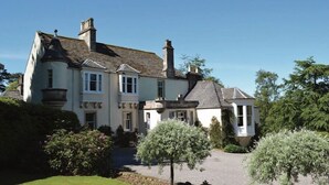 A large, multi-story house with a symmetrical facade, multiple chimneys, and a well-maintained garden. - Craigellachie Lodge (Aberlour)