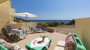 A terrace with a table set for dining, a chair, and a table with a white tablecloth. - Holiday House Myrtos (Rhodes)