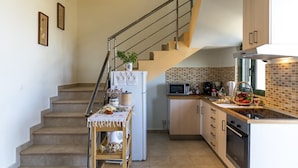 A kitchen with a microwave, stove, and sink. There is a staircase leading to another level. - Holiday House Myrtos (Rhodes)