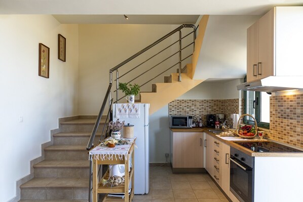 A kitchen with a microwave, stove, and sink. There is a staircase leading to another level. - Holiday House Myrtos (Rhodes)