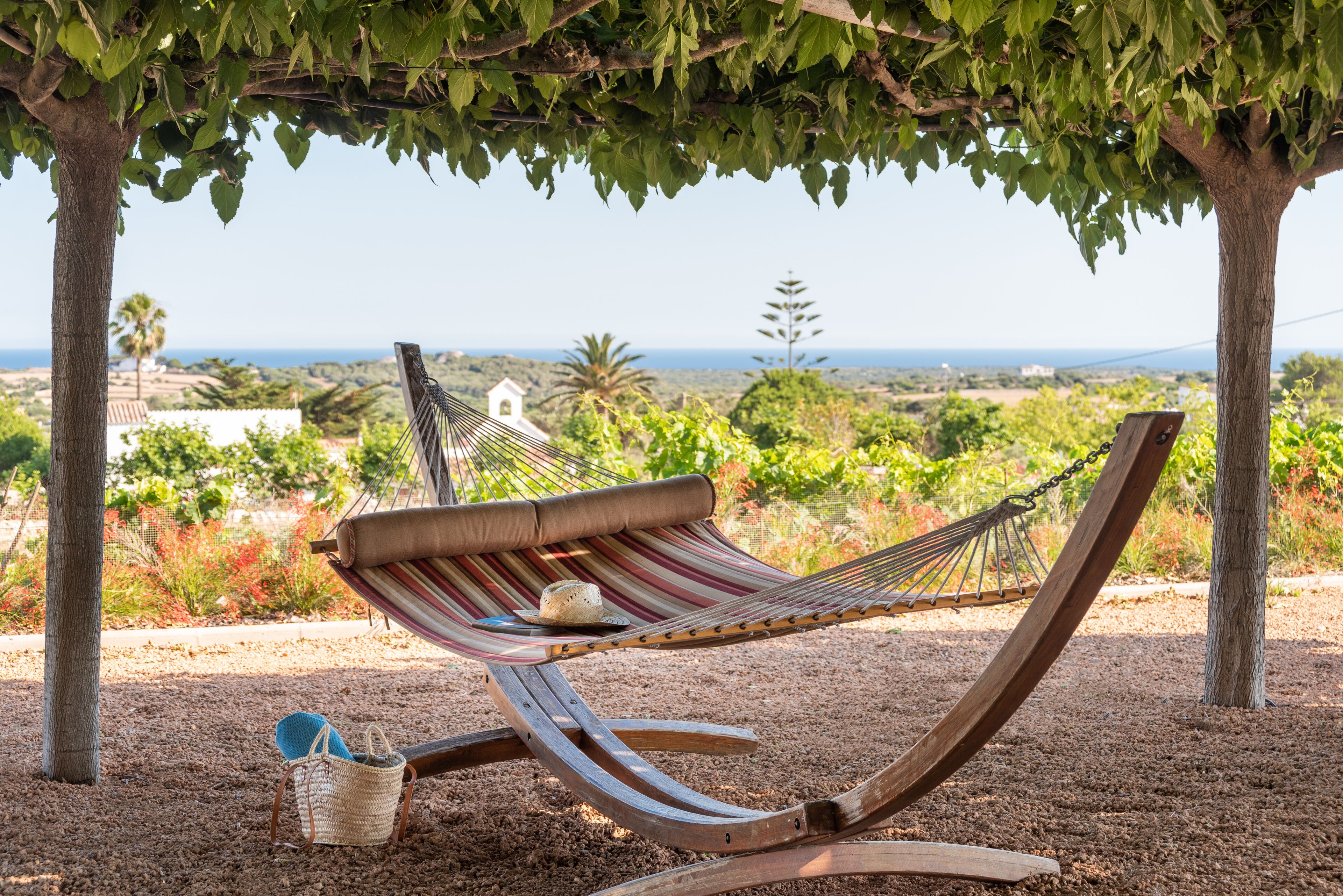 A hammock under a tree with a view of the landscape.