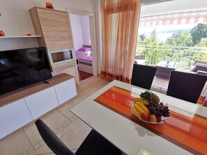 Relax in this stylish living room with a flat-screen TV, dining area, and balcony view.