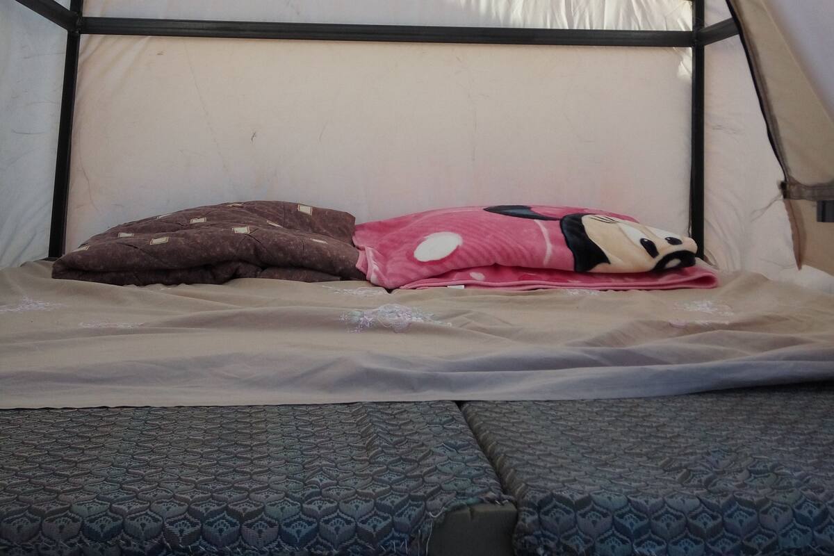 Une tente équipée d’un lit, comprenant un matelas, des oreillers et un auvent.