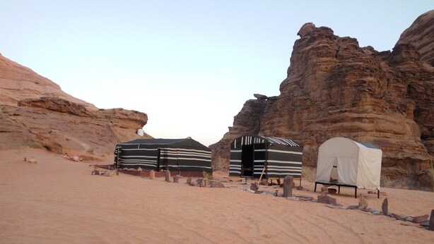 A desert campsite with tents and a rocky landscape. - Al sultan bedouin camp (Wadi Rum)