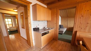 A wooden interior with a kitchen area, a sofa, and a visible window.
