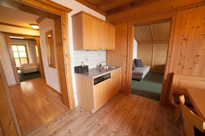 Un intérieur en bois comprenant un coin cuisine, un canapé et une fenêtre bien visible.
