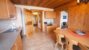 A wooden interior with a kitchen, dining area, and a hallway.