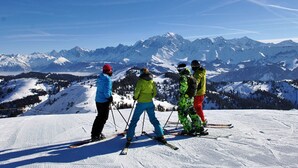 Eine Gruppe von Skifahrern auf einem verschneiten Hang, im Hintergrund ein Gebirge.