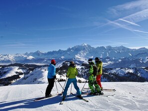 A group of skiers on a snowy slope with a mountain range in the background.