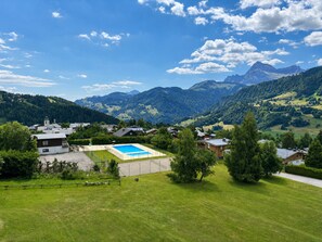 A residential area with a swimming pool, houses, and mountains in the background.