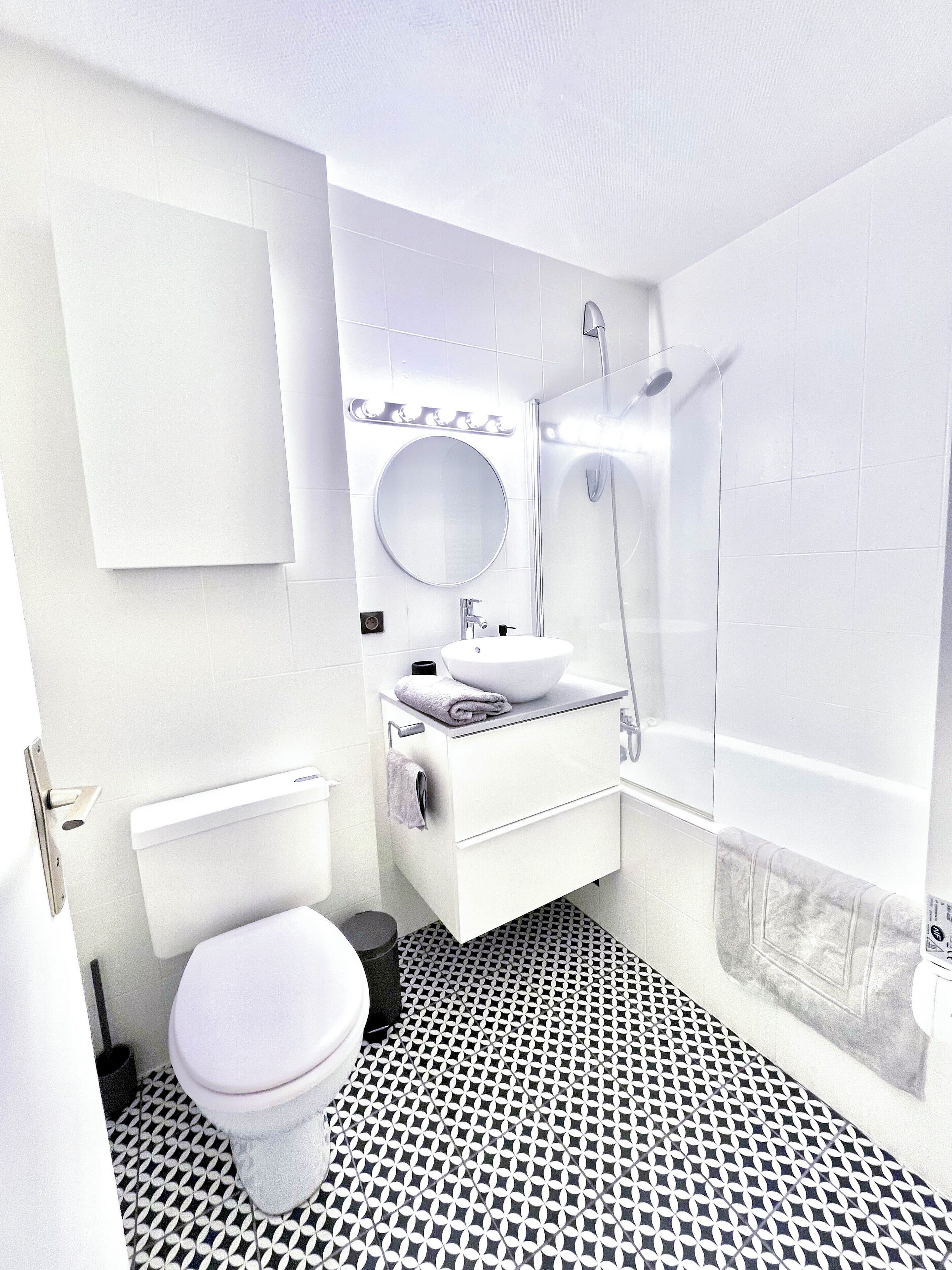 Un bagno moderno con un water bianco, un lavandino con uno specchio e una doccia.