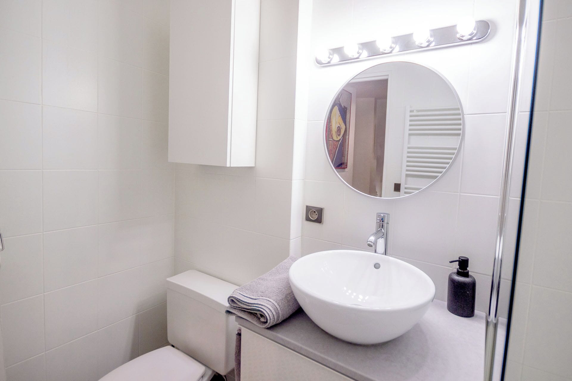 Un baño con un lavabo blanco, un espejo y una toalla en la encimera.