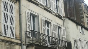 A historic building with multiple windows, a balcony, and a door.