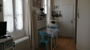 A compact kitchen with a dining table, chairs, a microwave, and a radiator.