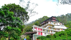 A multi-story building with balconies, surrounded by lush greenery and trees. - Grand Adams Peak Hotel (Nallathanniya)