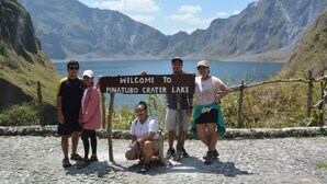 Un gruppo di persone davanti a un cartello di benvenuto al Lago del Cratere Pinatubo.