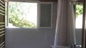 Un baño con bañera, ventana y espejo.