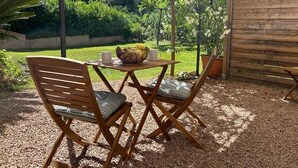 Un patio exterior con mobiliario de madera, una mesa y un frutero.