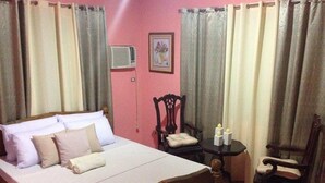 A bedroom with a bed, a chair, a small table, and a picture on the wall. - Bognot Lodge Mt Pinatubo Guesthouse (Capas)