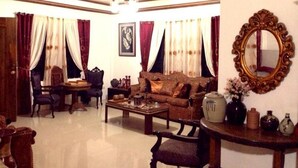 A traditional living room with a sofa, chairs, a coffee table, and a decorative mirror. - Bognot Lodge Mt Pinatubo Guesthouse (Capas)