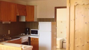 Una cucina compatta con mobili in legno, un fornello, un microonde e un frigorifero.