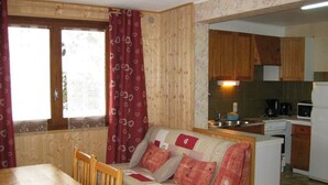 Una cucina compatta con mobili in legno, un tavolo da pranzo con sedie e un divano con cuscini decorati.