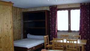 Una stanza con un letto a castello, un tavolo di legno con sedie e una finestra con tende.