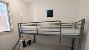 A bunk bed room with a window, a small bedside table, and a wall-mounted picture.