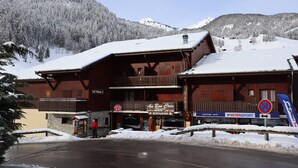 Ein Holzkonstrukt mit Restaurantschild, Sessellift und Bergblick.