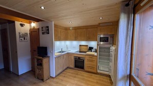Eine kleine Küche mit Holzausstattung, einer Mikrowelle und einem Kühlschrank.