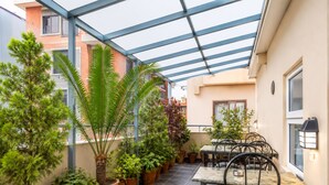 Un patio cubierto con macetas, mobiliario exterior y vistas del exterior del edificio.