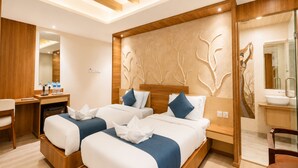 Habitación de hotel con dos camas, un escritorio y un baño.