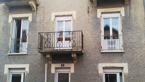 Un edificio de varios pisos con balcones, un coche estacionado en la entrada y una puerta con el número 4.