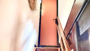 Una escalera de madera que conduce a una puerta con una cuerda colgada en la pared.