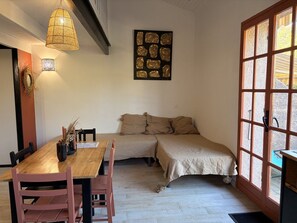 A room with a wooden dining table, chairs, a sofa, and a large window with a view.