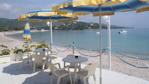 Terraza exterior con sombrillas, vista al mar y una barrera de cuerda.